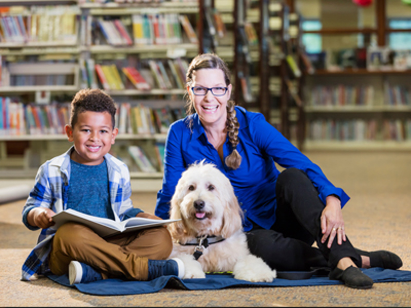 Teacher, student and dog reading a book